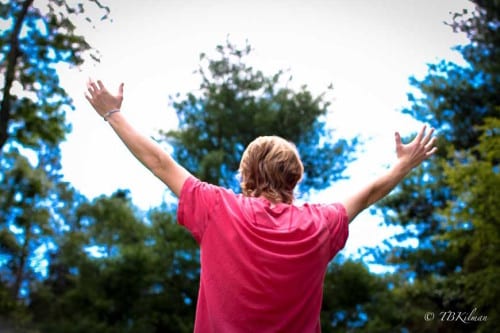 young adult with arms raised high 