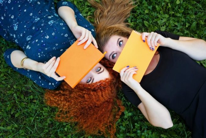 Two teen girls hiding behind books
