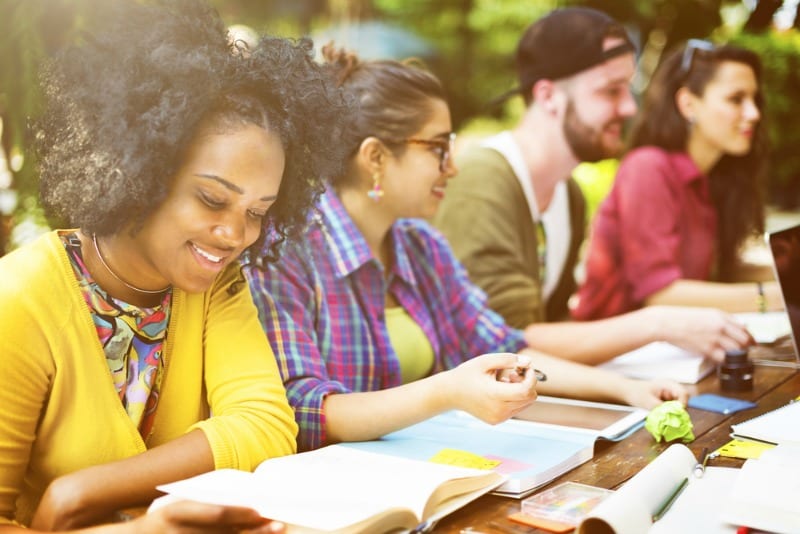 African American woman with yellow sweater studying with friends