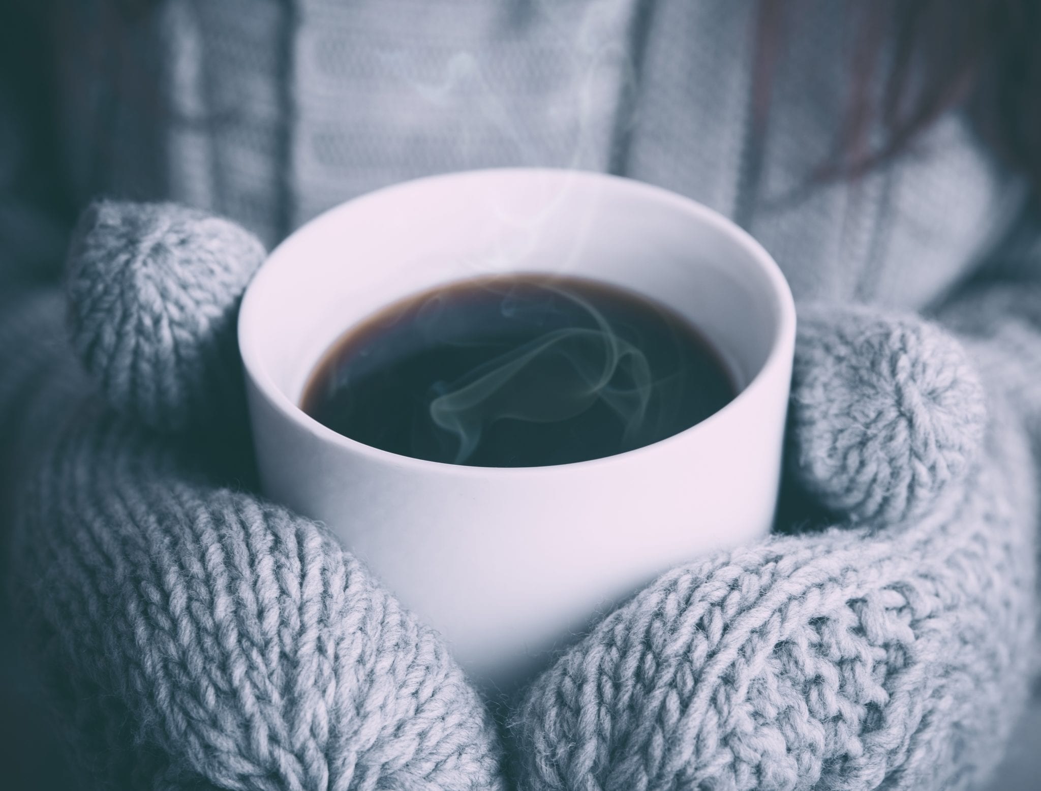 woman in mittens holding hot coffee