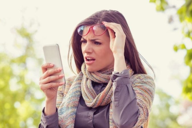 woman looking at cell phone shocked