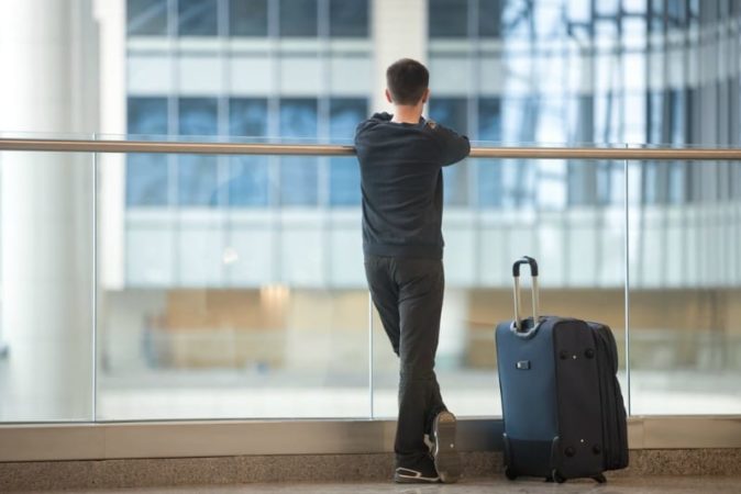 Teen boy with suitcase waiting for flight