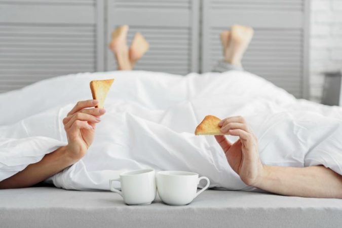 Couple in bed with toast and coffee after having sex