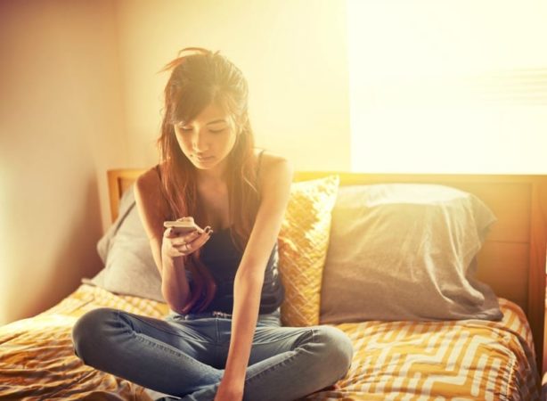 Teen girl on bed with smartphone