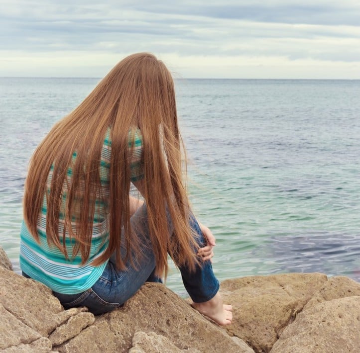 teen girl sitting by water