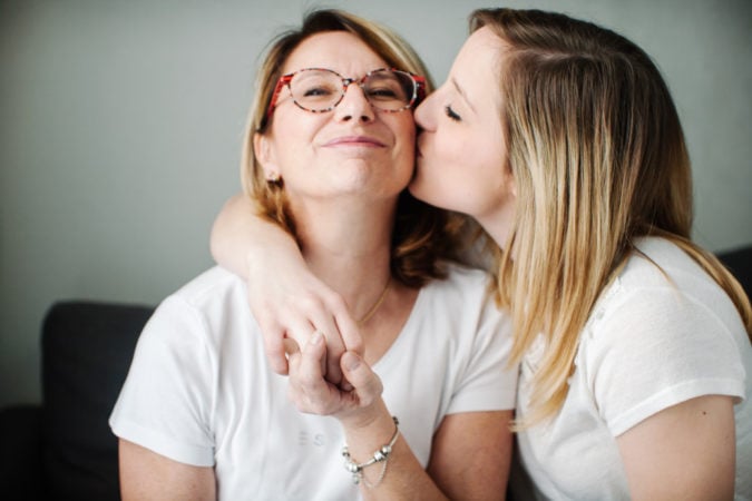 Adult daughter kissing mother on cheek