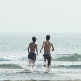 two brothers running into the ocean