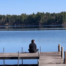 girl sitting on dock at lake