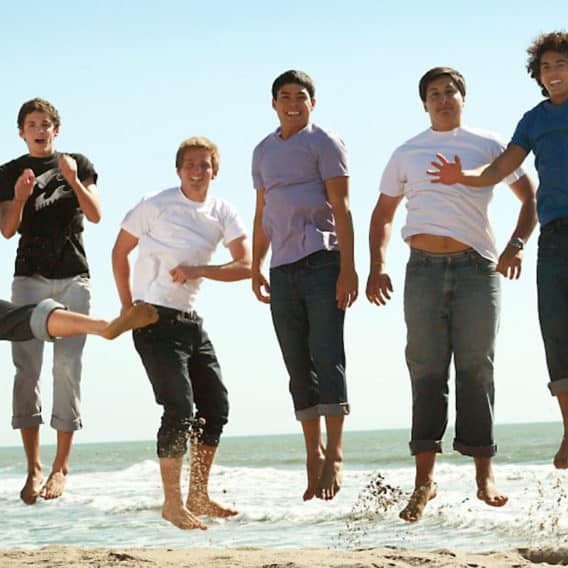 teen boys jumping in surf