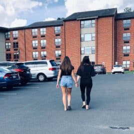 two daughters walking into college dorm