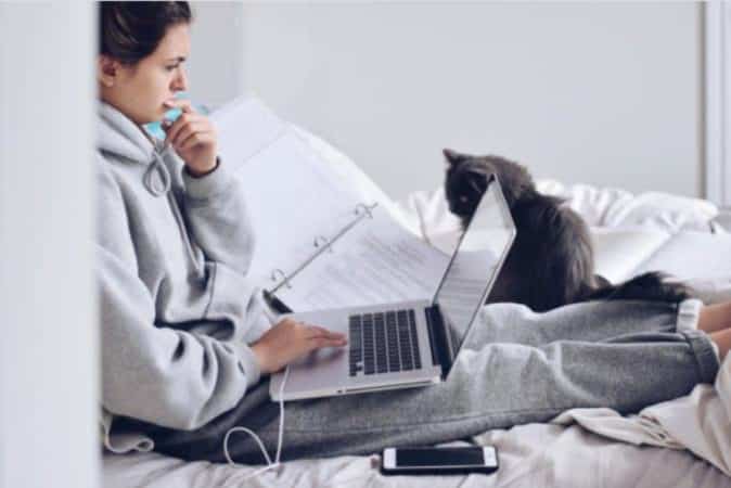teen on bed cat computer