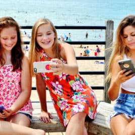 3 teen girls at beach with phones