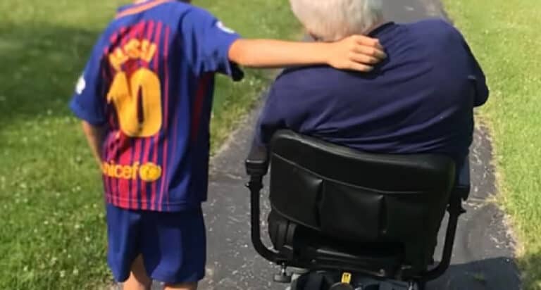 young boy walking with grandfather in wheelchair