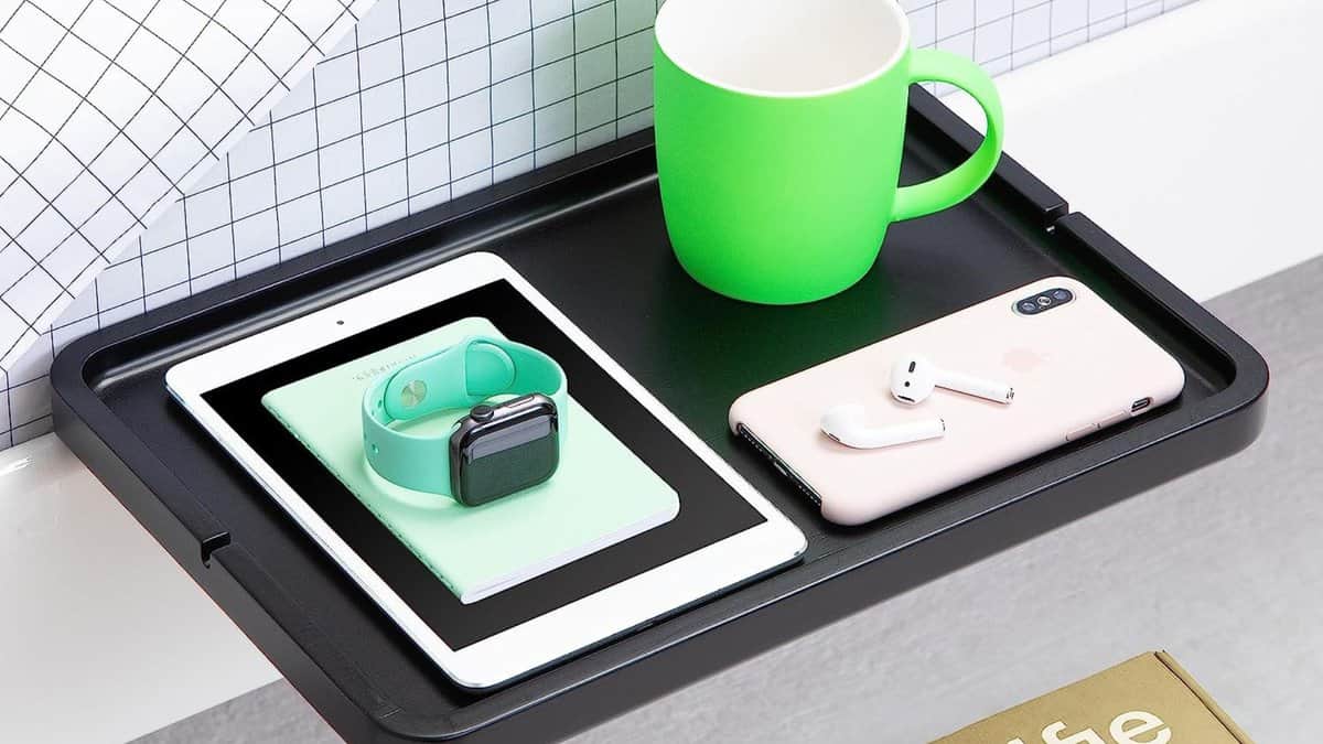 A BedShelfie bedside shelf holding a mug, a phone, and a tablet. 