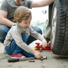 Little boy with dad changing tire on car