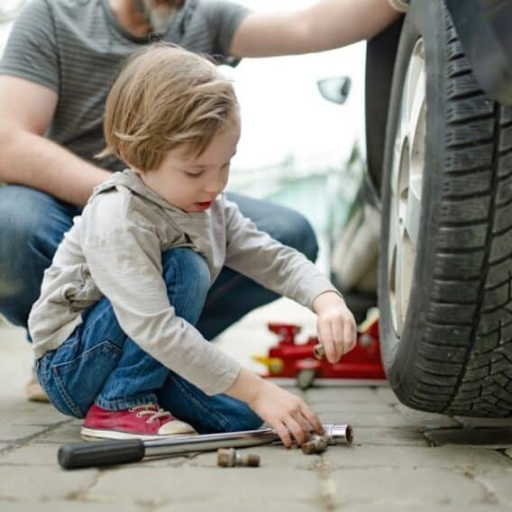 Little boy with dad changing tire on car