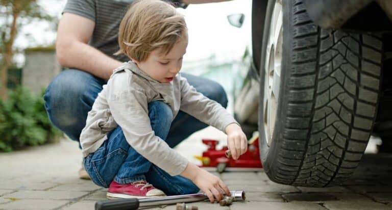 Little boy with dad changing tire on car