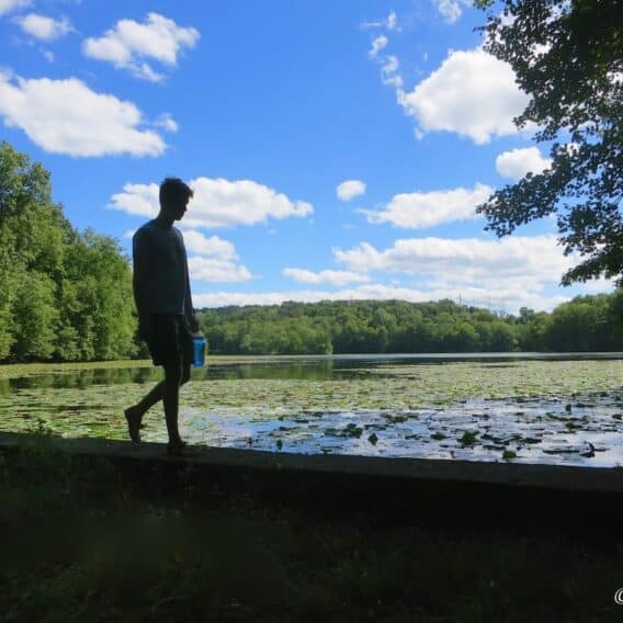young adult walking by a lake