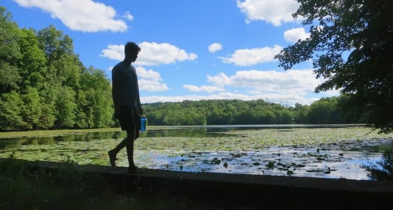 young adult walking by a lake